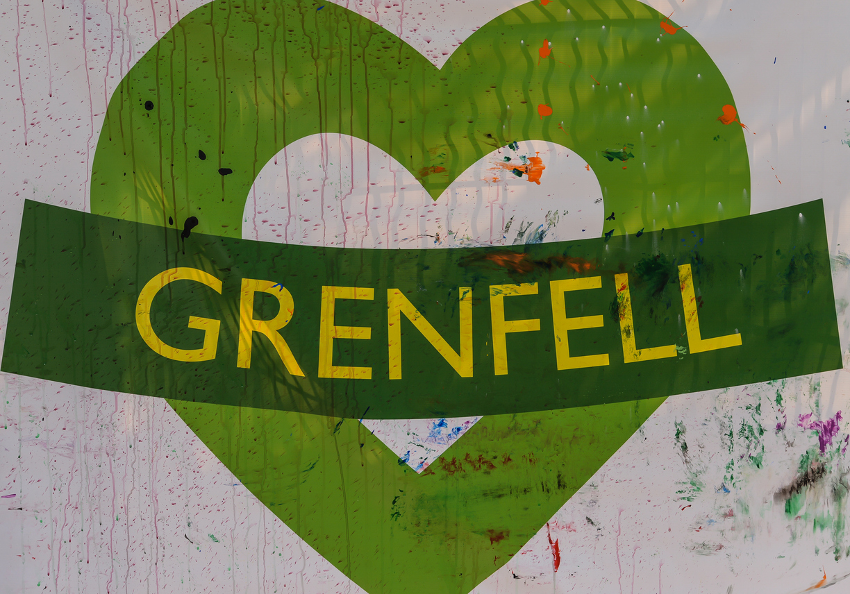 the iconic green grenfell heart with a strip across saying grenfell with multicoloured paint smeared across it