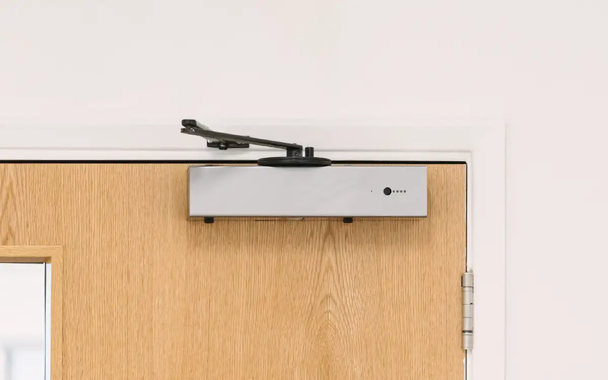 The Freedor Pro free- swing door opener attached to the top of a fire door