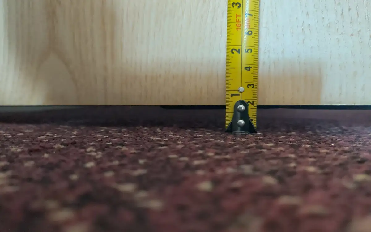 A tape measure against a fire door showing the gaps between the bottom of the door and the floor