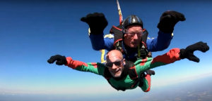Two men in harnesses mid air during a skydive.