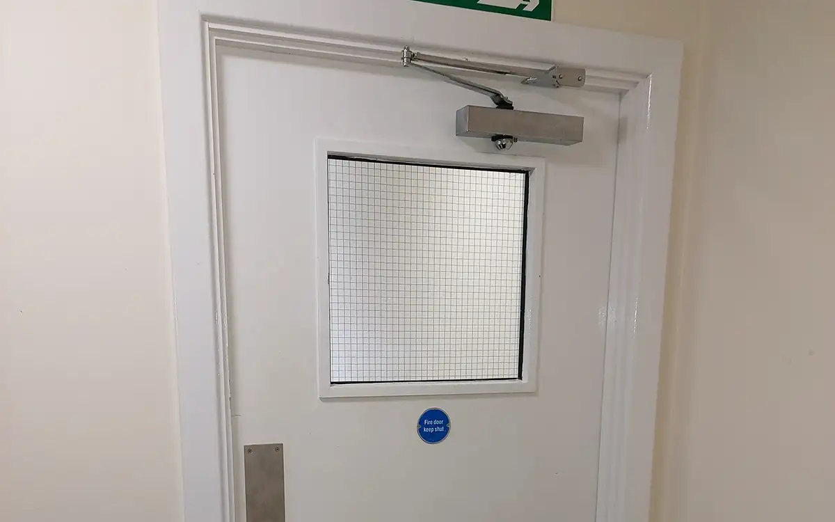 A fire door with a standard fire door closer installed at the top of it.