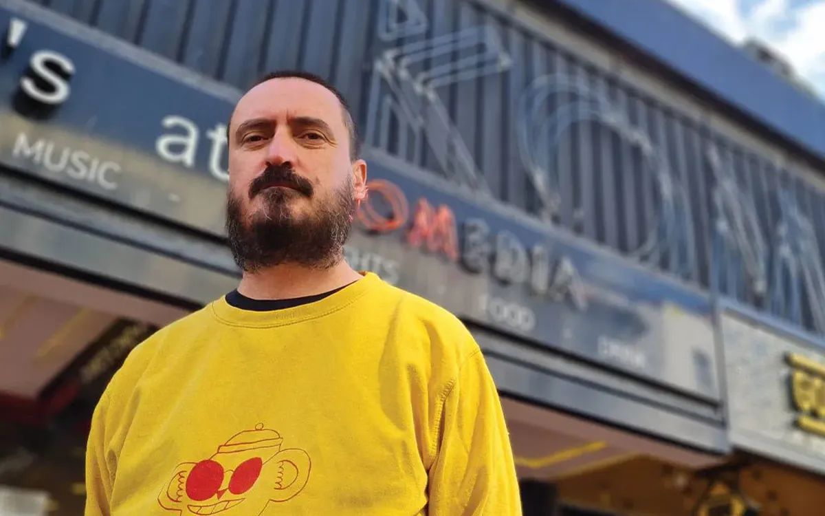 A man wearing a yellow jumper, stood outside the Komedia venue