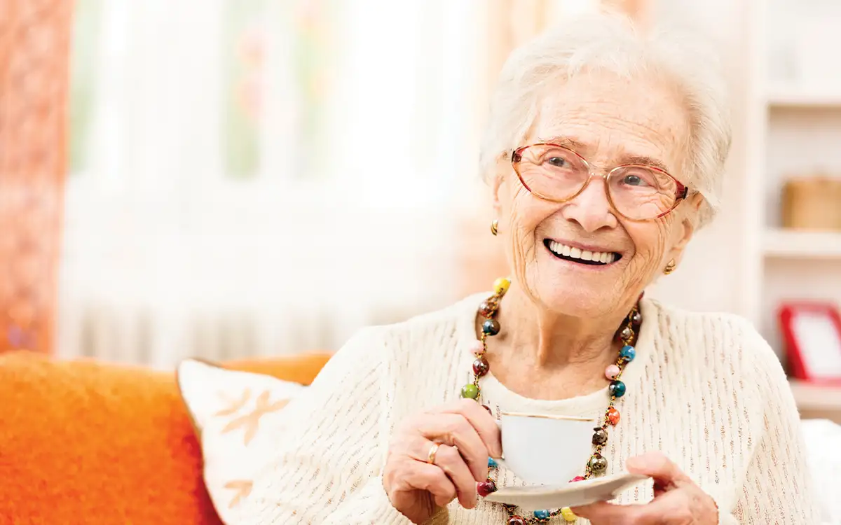 Smiling elderly lady holding a cup of tea