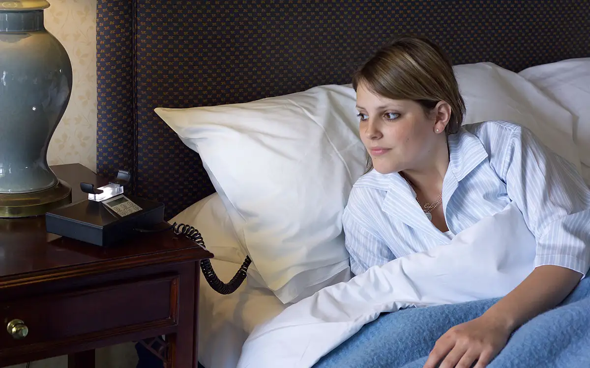 A person staying in a hotel with the Deafgard vibration pad under her pillow