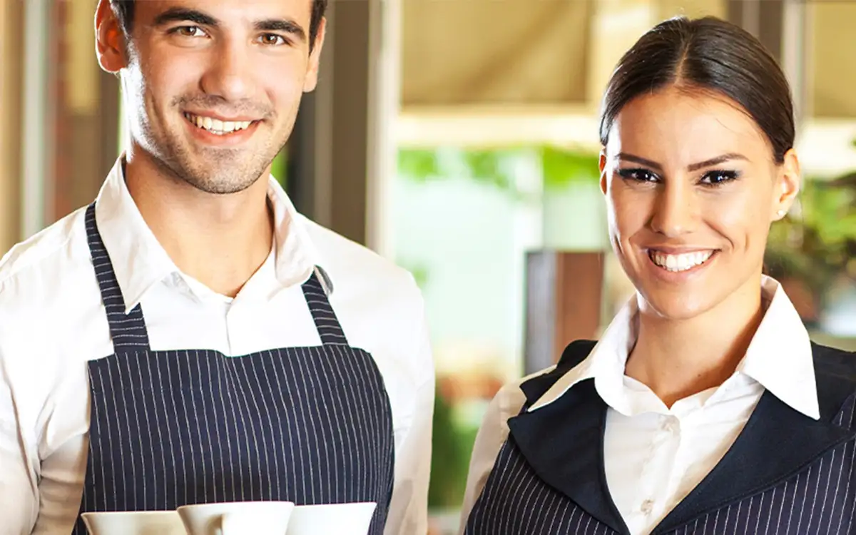 a smiling man and woman working in hospitality
