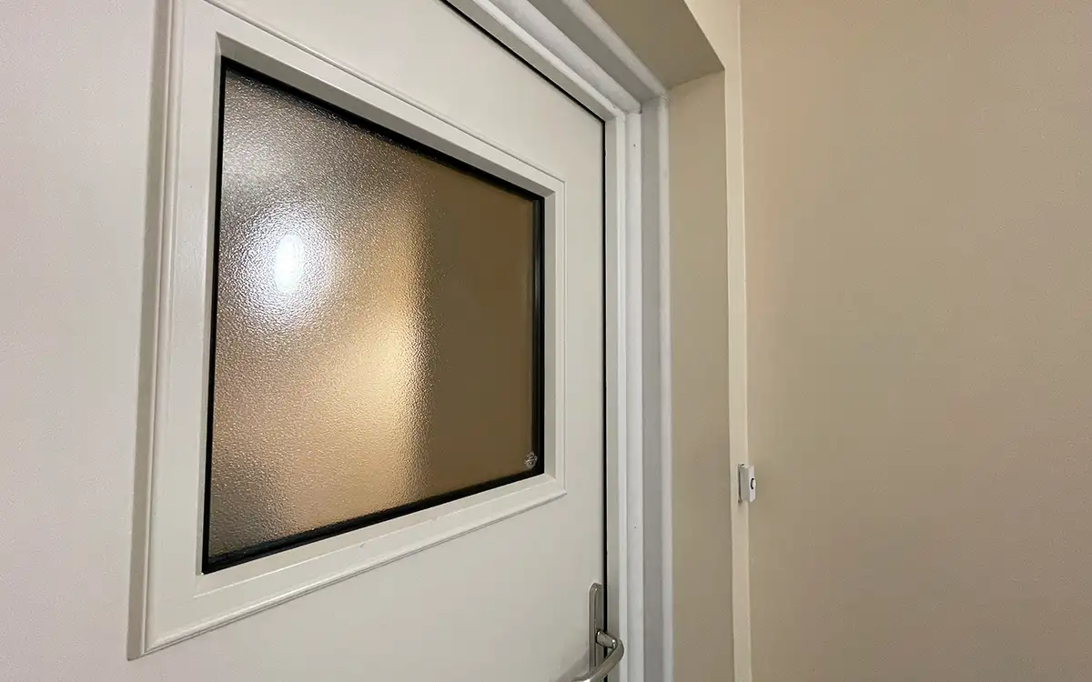 A white fire door with a vision panel, installed by Fireco